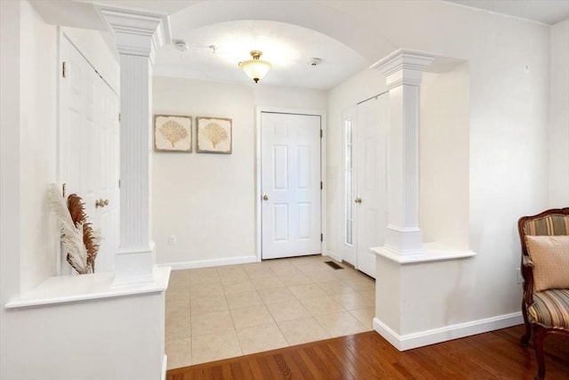 foyer entrance featuring decorative columns and light hardwood / wood-style floors