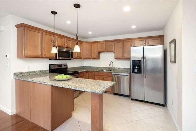 kitchen featuring appliances with stainless steel finishes, pendant lighting, sink, light stone counters, and kitchen peninsula