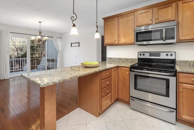 kitchen featuring light stone counters, an inviting chandelier, hanging light fixtures, appliances with stainless steel finishes, and kitchen peninsula