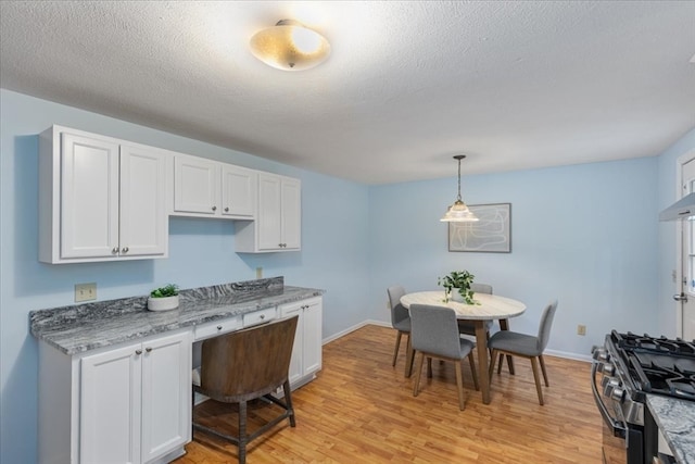 kitchen featuring light hardwood / wood-style flooring, white cabinets, hanging light fixtures, and stainless steel gas range