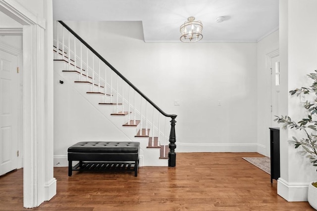 foyer entrance featuring hardwood / wood-style flooring, ornamental molding, and an inviting chandelier