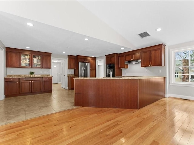 kitchen featuring light wood finished floors, lofted ceiling, stainless steel fridge, oven, and a peninsula