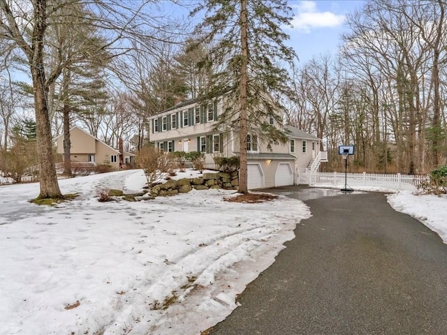 view of front of home with a garage, aphalt driveway, and fence