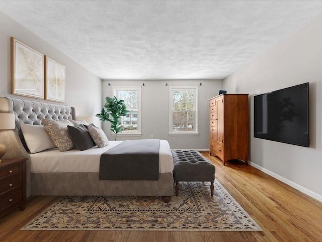 bedroom featuring a textured ceiling, wood finished floors, and baseboards