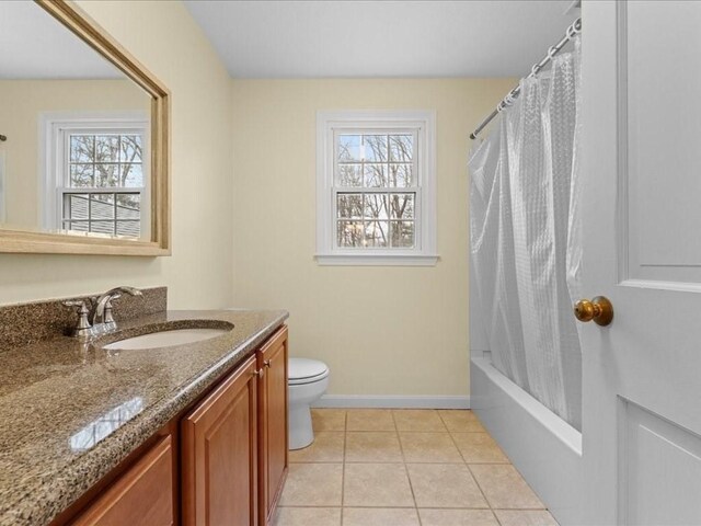 full bathroom with a wealth of natural light, tile patterned flooring, vanity, and baseboards