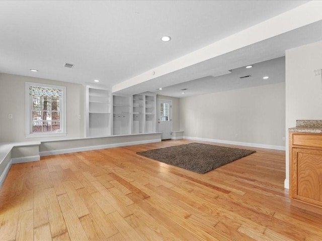 unfurnished living room with visible vents, plenty of natural light, light wood-style flooring, and baseboards