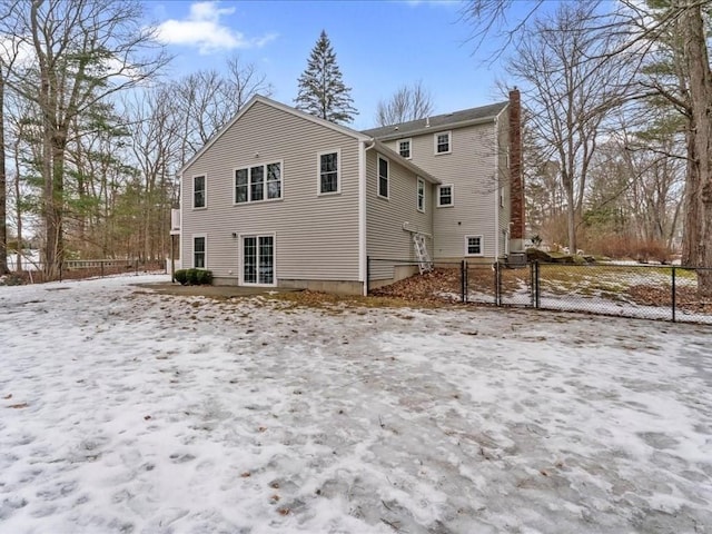 snow covered property with a gate, fence, and a chimney