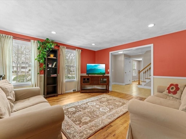 living area with baseboards, stairway, wood finished floors, a textured ceiling, and recessed lighting