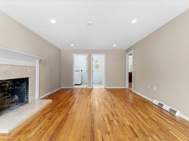 unfurnished living room with light wood-style flooring, a fireplace, visible vents, and baseboards