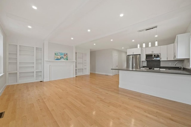 kitchen featuring stainless steel appliances, sink, pendant lighting, built in features, and white cabinets