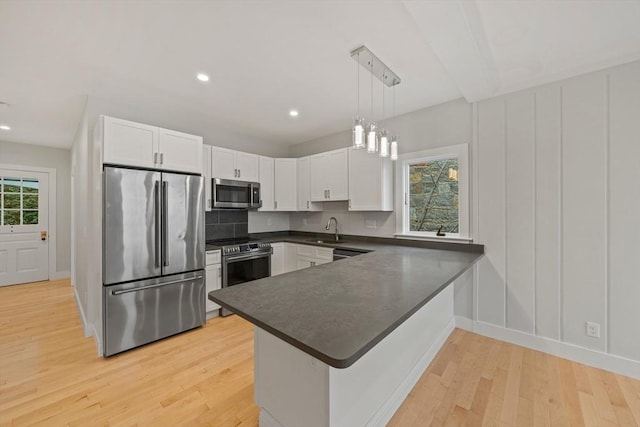 kitchen with sink, hanging light fixtures, stainless steel appliances, kitchen peninsula, and white cabinets