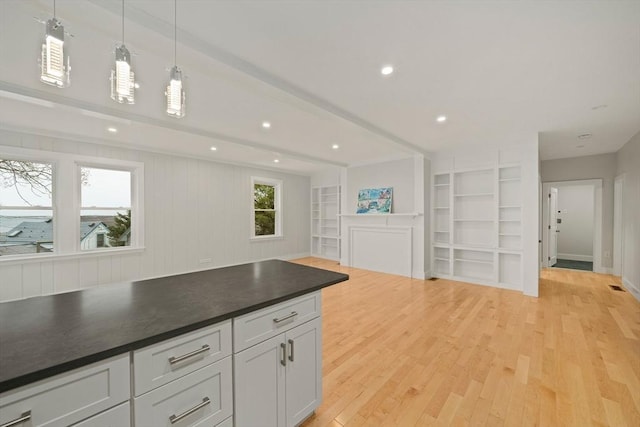 kitchen with built in shelves, beam ceiling, decorative light fixtures, light hardwood / wood-style flooring, and white cabinets