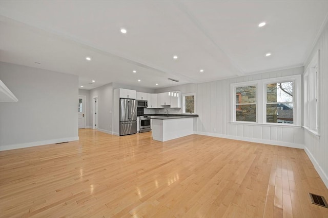 unfurnished living room featuring a healthy amount of sunlight, light wood-type flooring, and sink