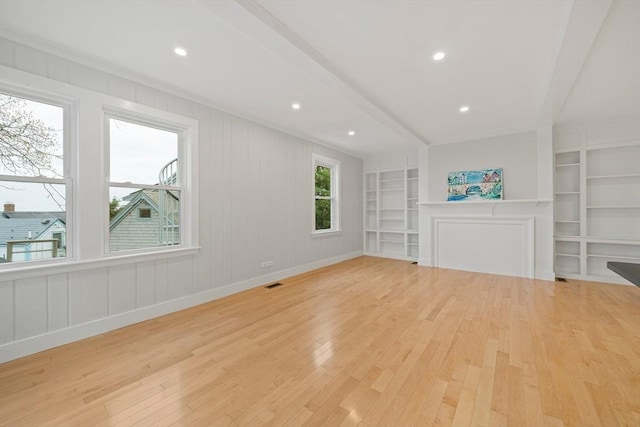 unfurnished living room with built in shelves and light hardwood / wood-style floors