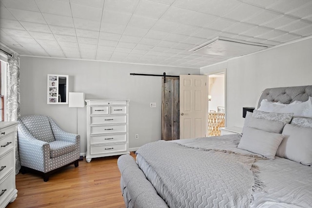 bedroom with a barn door and light wood-type flooring