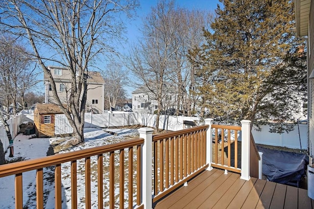 snow covered deck featuring a storage shed