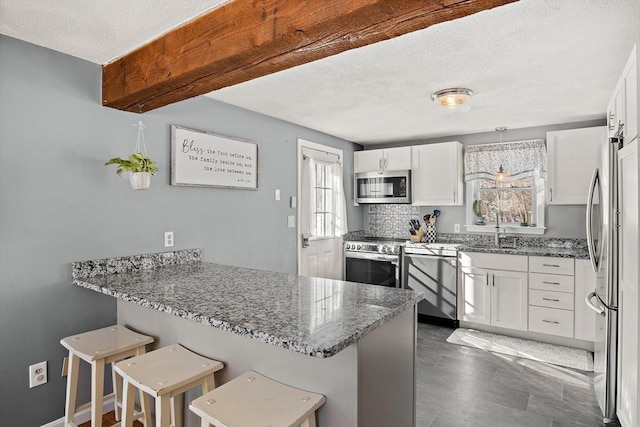 kitchen featuring white cabinetry, a breakfast bar, stainless steel appliances, and kitchen peninsula