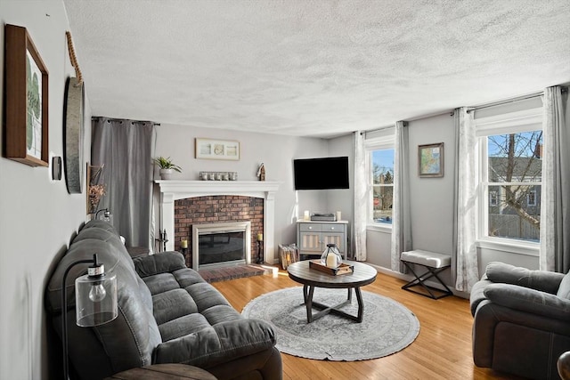 living room with a textured ceiling, a fireplace, and light hardwood / wood-style flooring