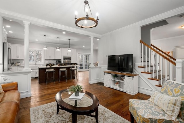 living room with dark wood-type flooring, stairs, wainscoting, ornate columns, and crown molding