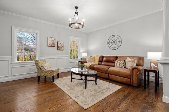 living area featuring a decorative wall, a wainscoted wall, a notable chandelier, ornamental molding, and dark wood-style floors