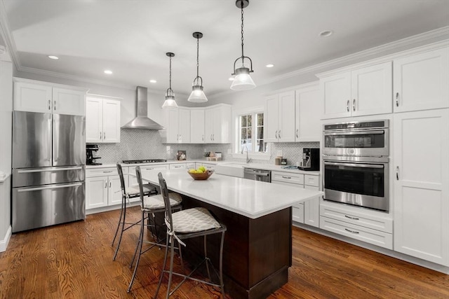 kitchen with white cabinets, wall chimney exhaust hood, appliances with stainless steel finishes, and light countertops