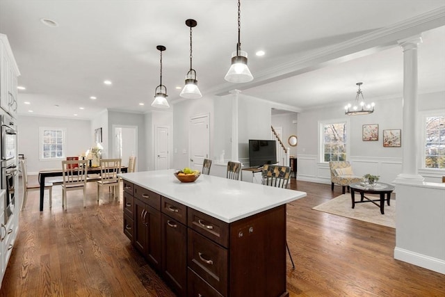 kitchen with white cabinets, light countertops, dark brown cabinets, dark wood finished floors, and ornate columns