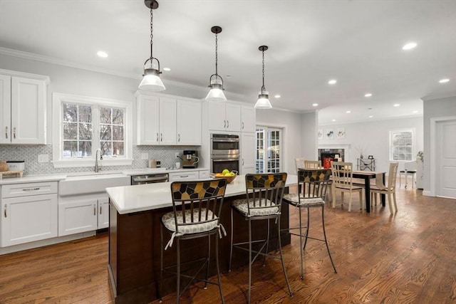 kitchen featuring a fireplace, a kitchen island, a sink, appliances with stainless steel finishes, and decorative backsplash