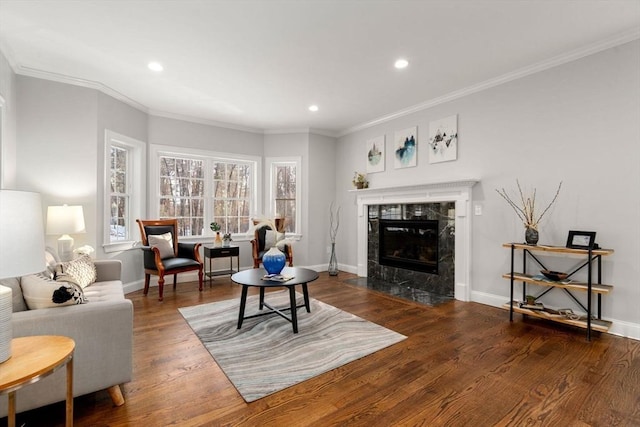 living area with crown molding, a fireplace, baseboards, and wood finished floors