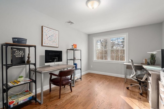 office area with wood finished floors, visible vents, and baseboards