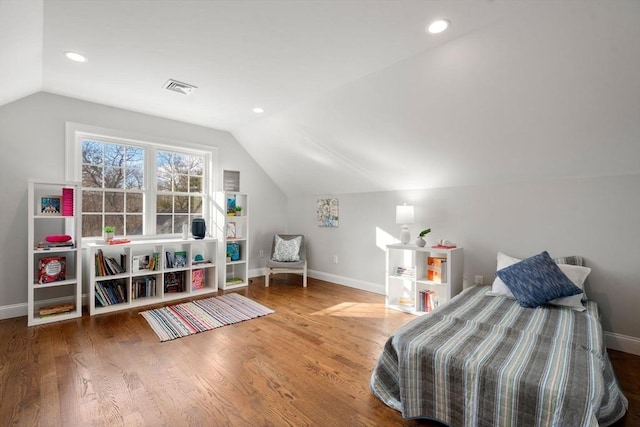 bedroom featuring baseboards, visible vents, vaulted ceiling, and wood finished floors