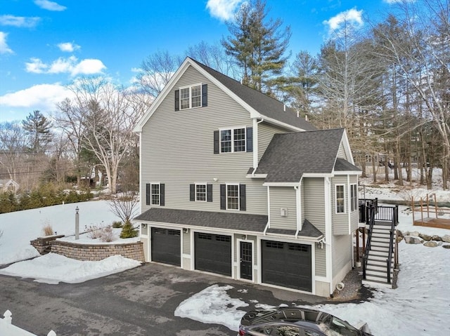 view of front of house with a garage, a shingled roof, stairway, and aphalt driveway