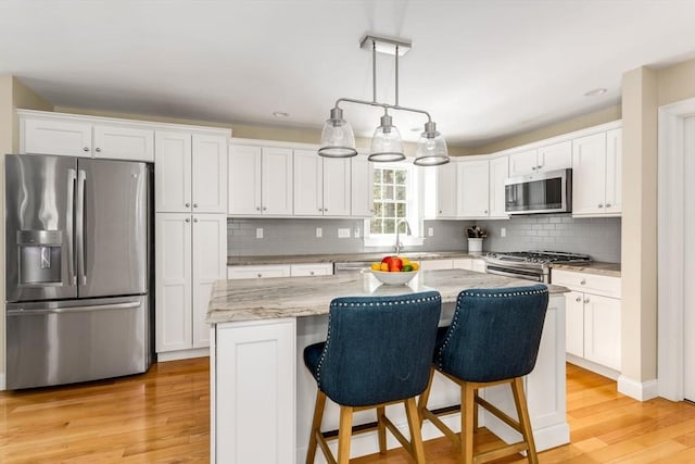 kitchen featuring stainless steel appliances, light wood-type flooring, a center island, and white cabinetry