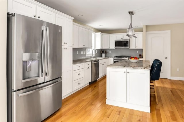 kitchen featuring stainless steel appliances, light wood-type flooring, decorative backsplash, and white cabinets