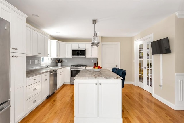 kitchen with appliances with stainless steel finishes, a center island, a sink, and light wood-style flooring