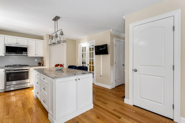 kitchen featuring appliances with stainless steel finishes, white cabinetry, light wood-style flooring, and backsplash