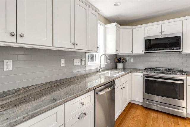 kitchen featuring stainless steel appliances, light wood-style floors, white cabinetry, and a sink