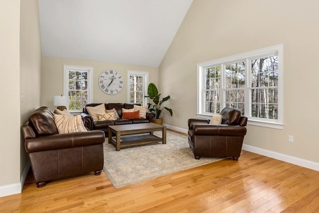 living area featuring light wood-style floors, baseboards, and high vaulted ceiling