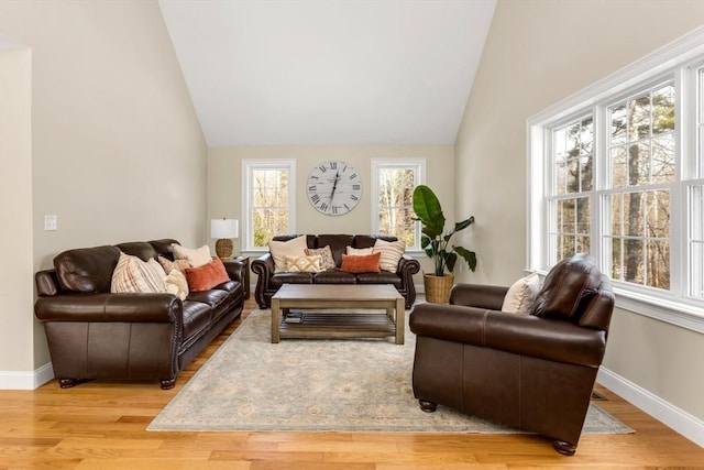 living area featuring light wood-style flooring, baseboards, and vaulted ceiling