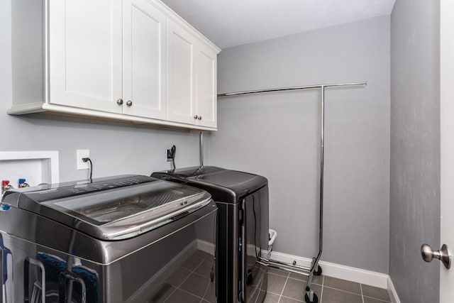 laundry room with dark tile patterned flooring, separate washer and dryer, cabinet space, and baseboards