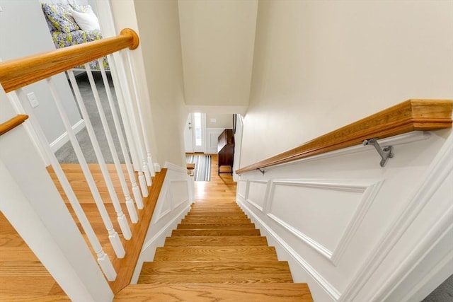 stairway featuring a wealth of natural light, wainscoting, and a decorative wall