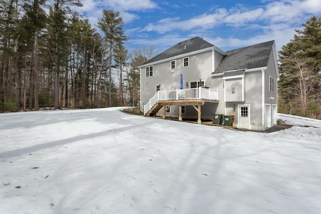 rear view of property featuring a garage, stairway, and a deck