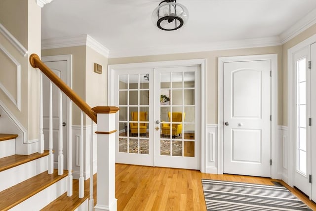 doorway to outside featuring ornamental molding, french doors, light wood finished floors, and stairs