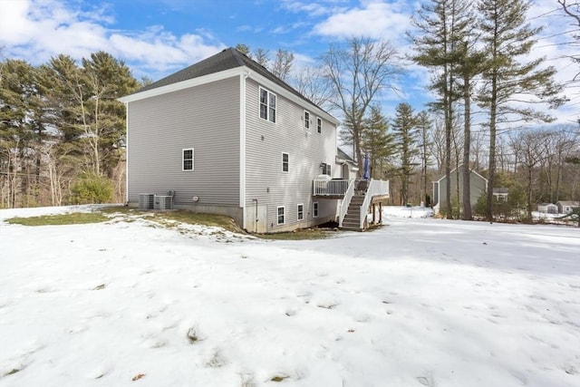 snow covered property with a deck, stairway, and cooling unit