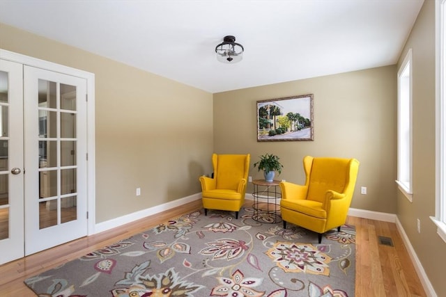 living area featuring baseboards, visible vents, wood finished floors, and french doors