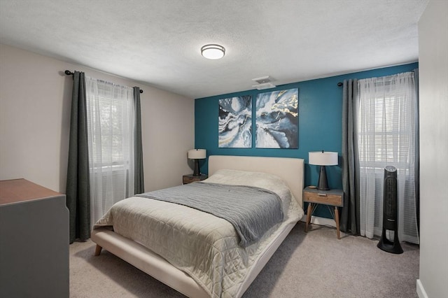 bedroom with visible vents, light carpet, and a textured ceiling