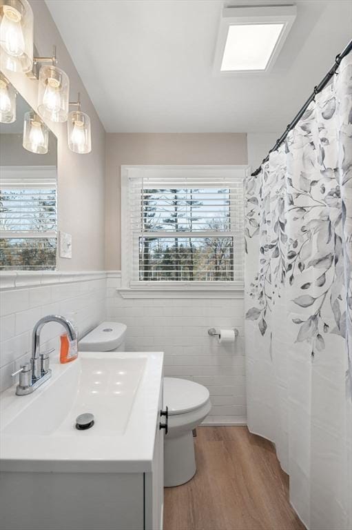 bathroom featuring toilet, a shower with shower curtain, wood finished floors, vanity, and tile walls