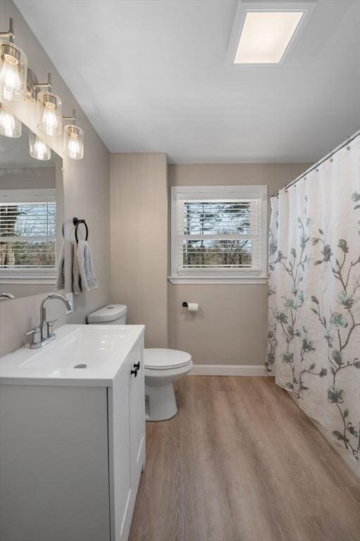 full bath featuring a wealth of natural light, vanity, toilet, and wood finished floors