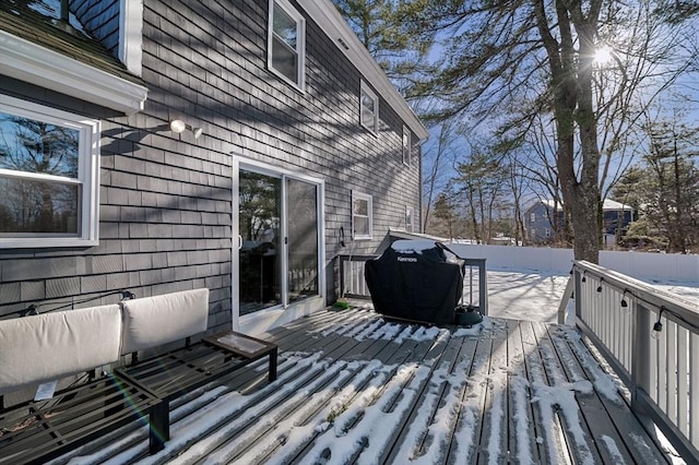 snow covered deck featuring a grill and fence