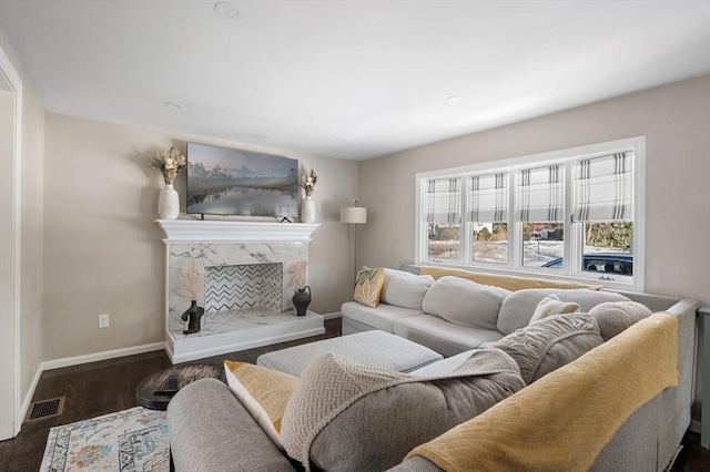 living room with dark wood-type flooring, a premium fireplace, visible vents, and baseboards