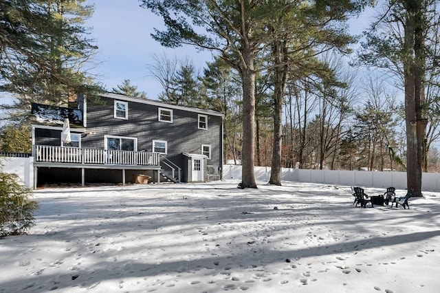 snow covered rear of property with a wooden deck and fence